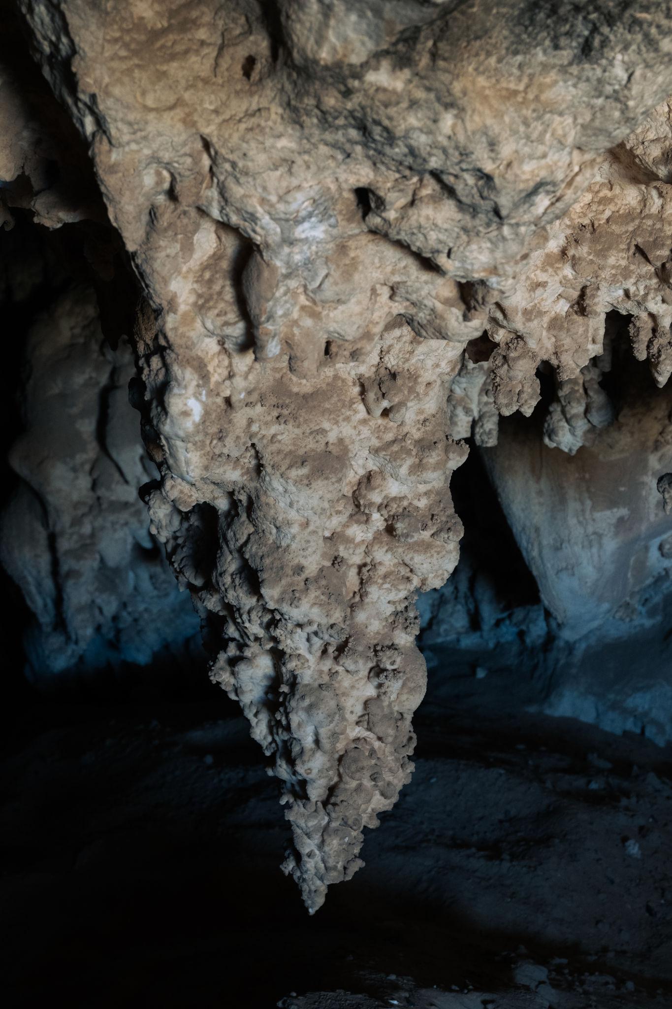 A large rough stalactite hanging from a limestone cave ceiling in Bahariya Oasis
