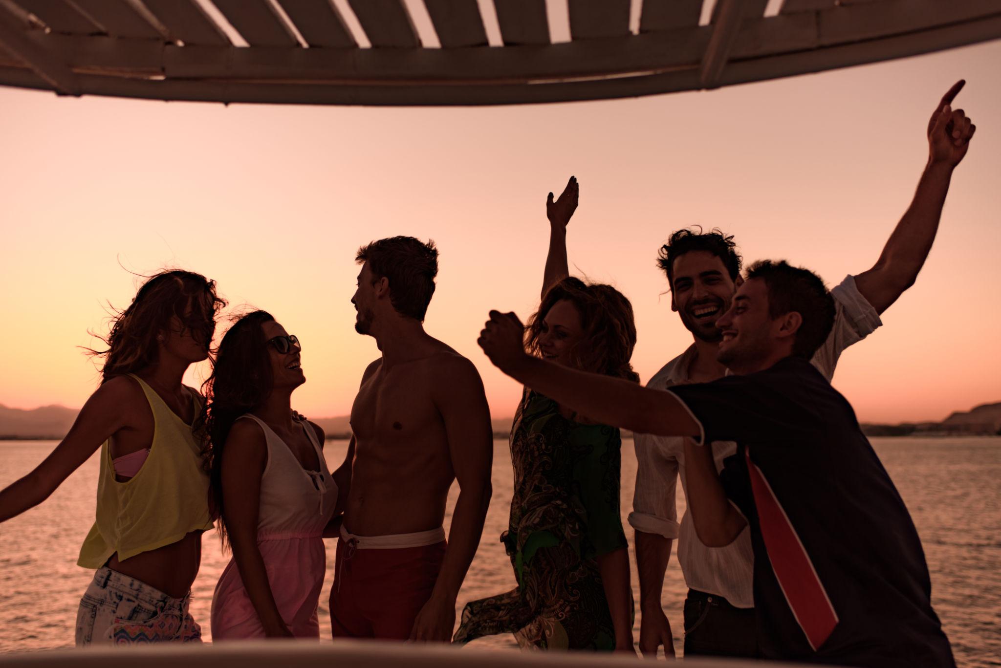 Group of friends dancing and celebrating on a boat deck at Red Sea sunset