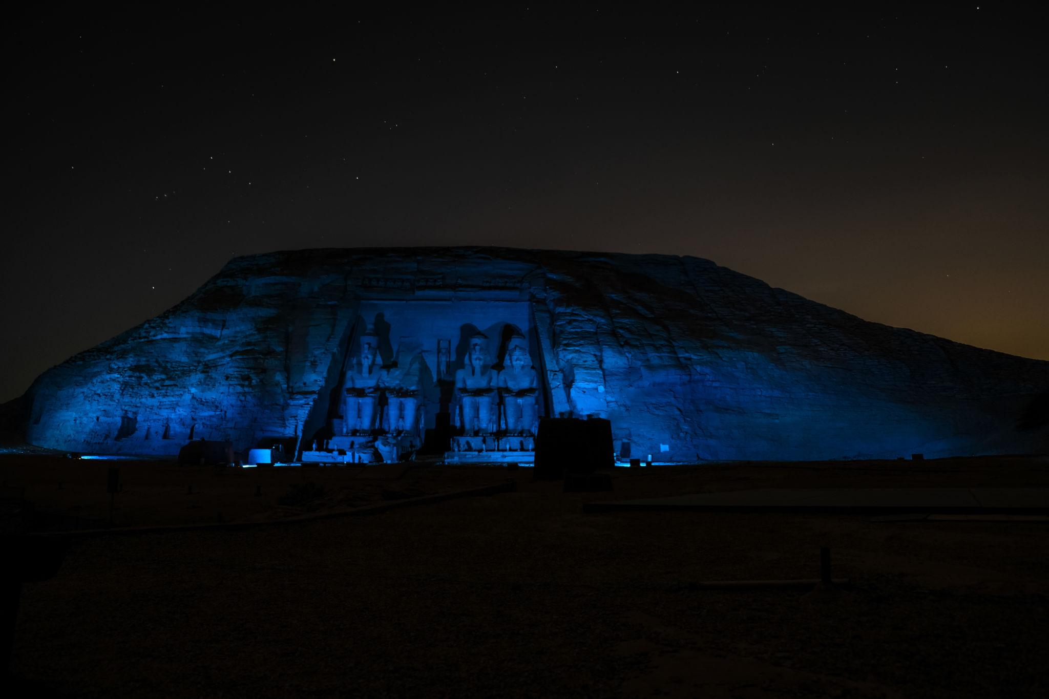Abu Simbel temple facade dramatically lit in blue light under a starry night sky
