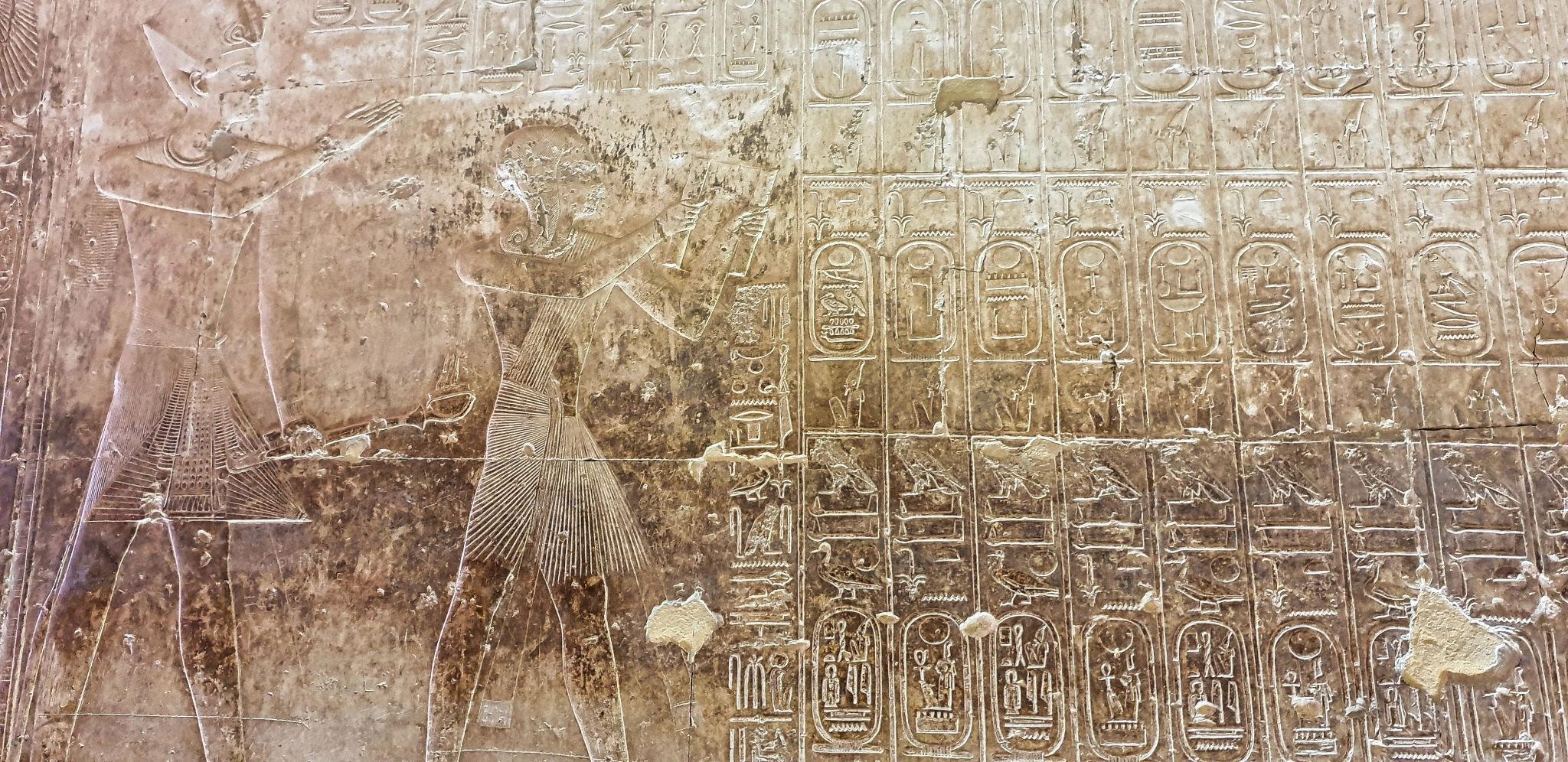 Wide view of the Abydos King List with a pharaoh presenting offerings to ancestors.