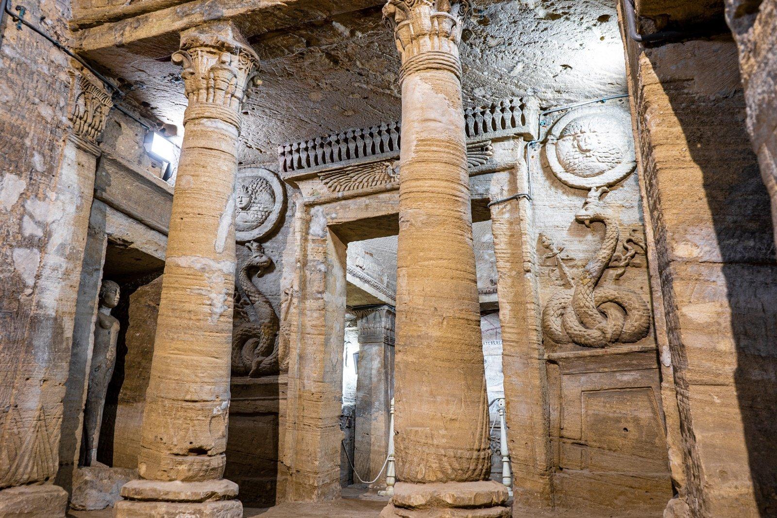 Massive rock-cut columns and carved reliefs inside the rotunda hall of the Alexandria catacombs