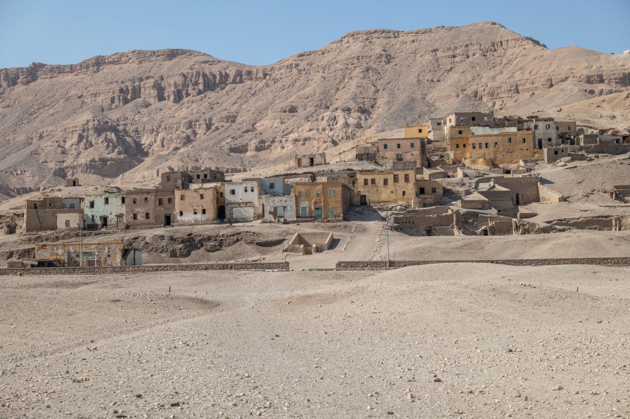 Modern village houses on the Theban hillside near Deir el-Medina with limestone cliffs behind