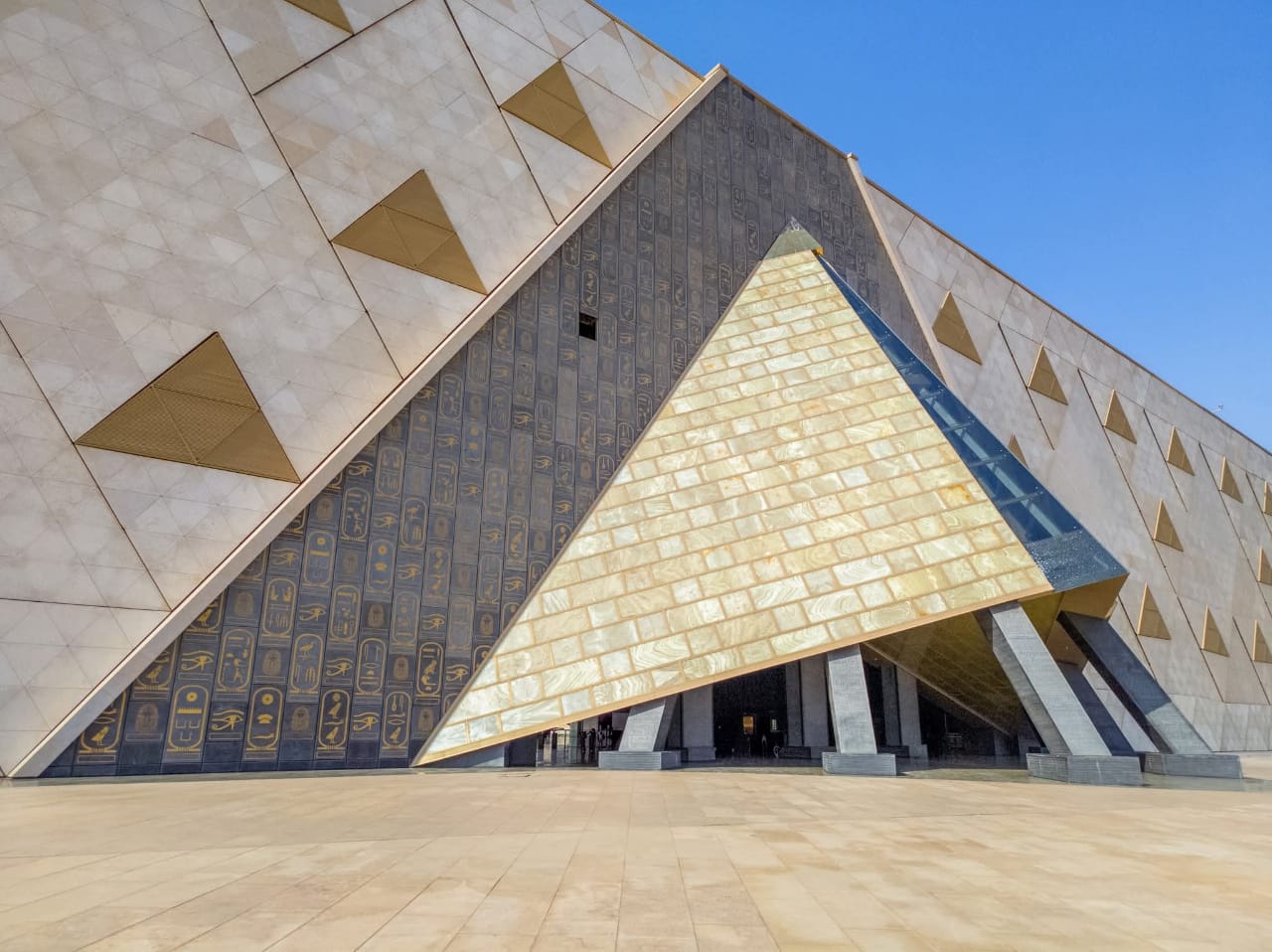 NMEC's dramatic triangular entrance with golden hieroglyphic panels under a clear blue sky