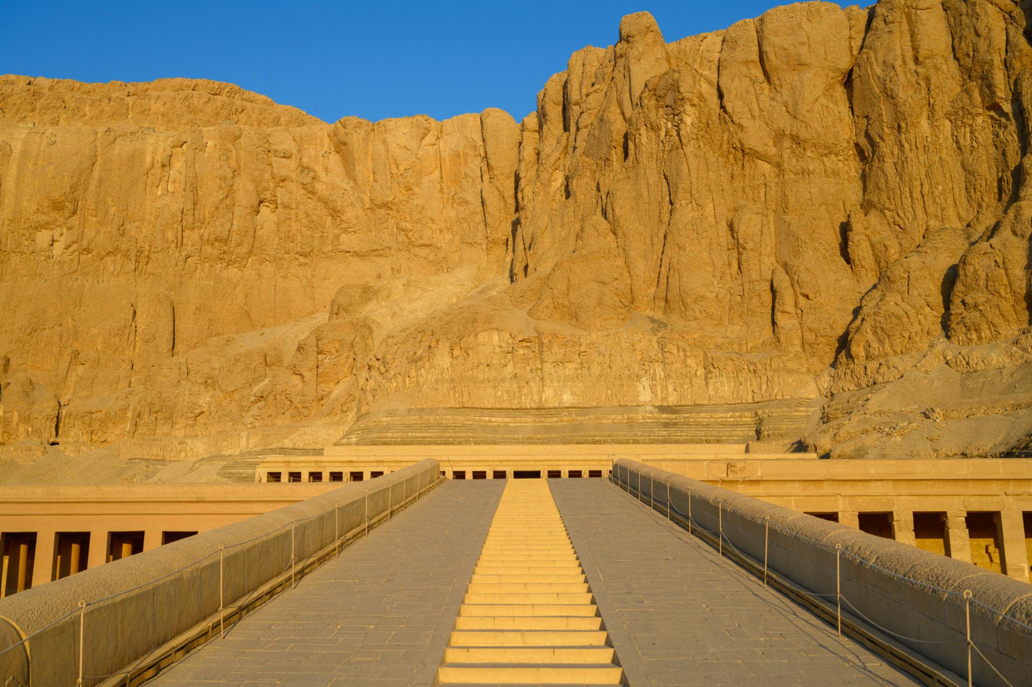 Golden sunset light on the ramp to Hatshepsut Temple and towering cliffs