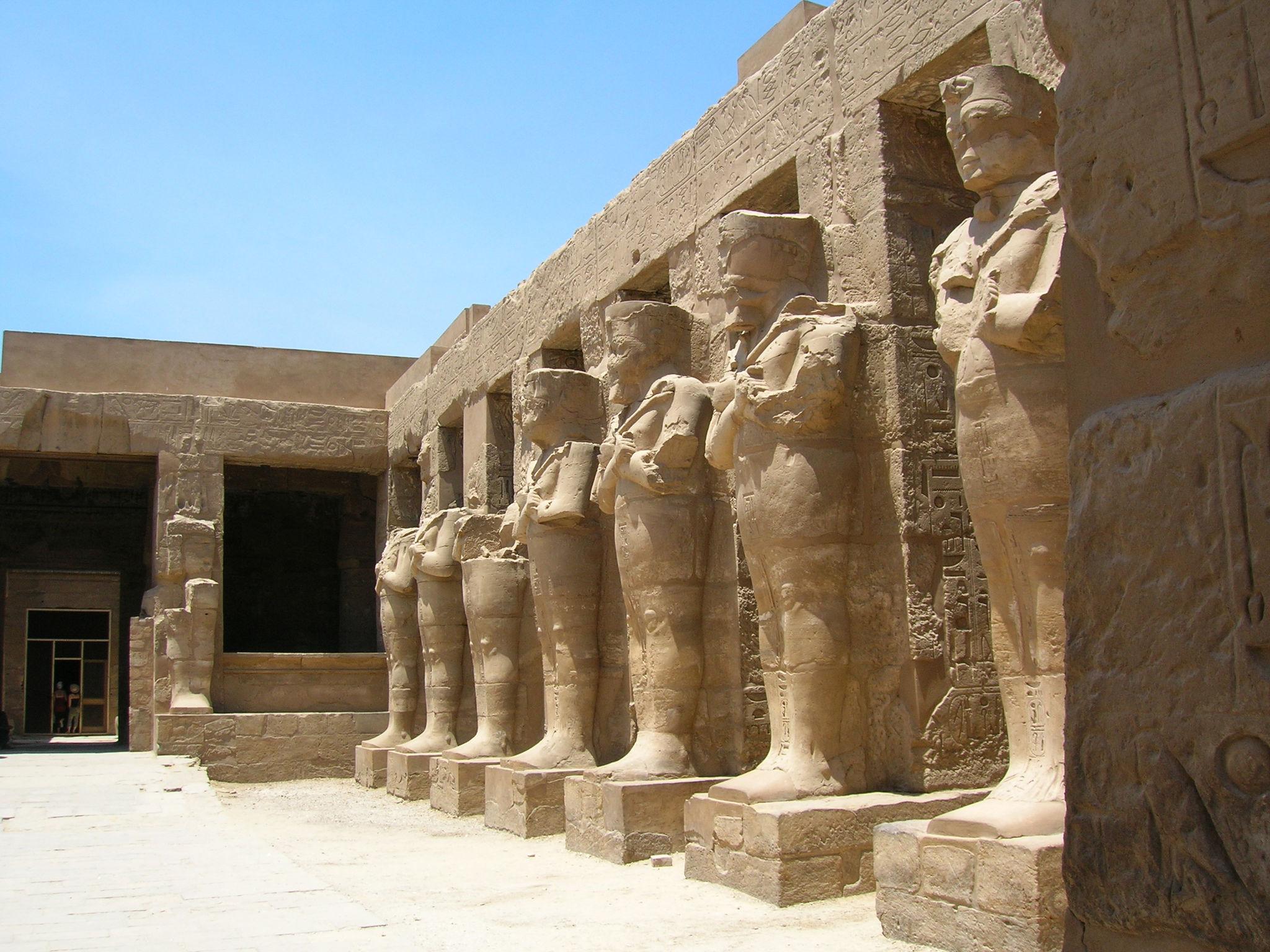 Row of Osiride pharaoh statues lining a courtyard at Karnak Temple