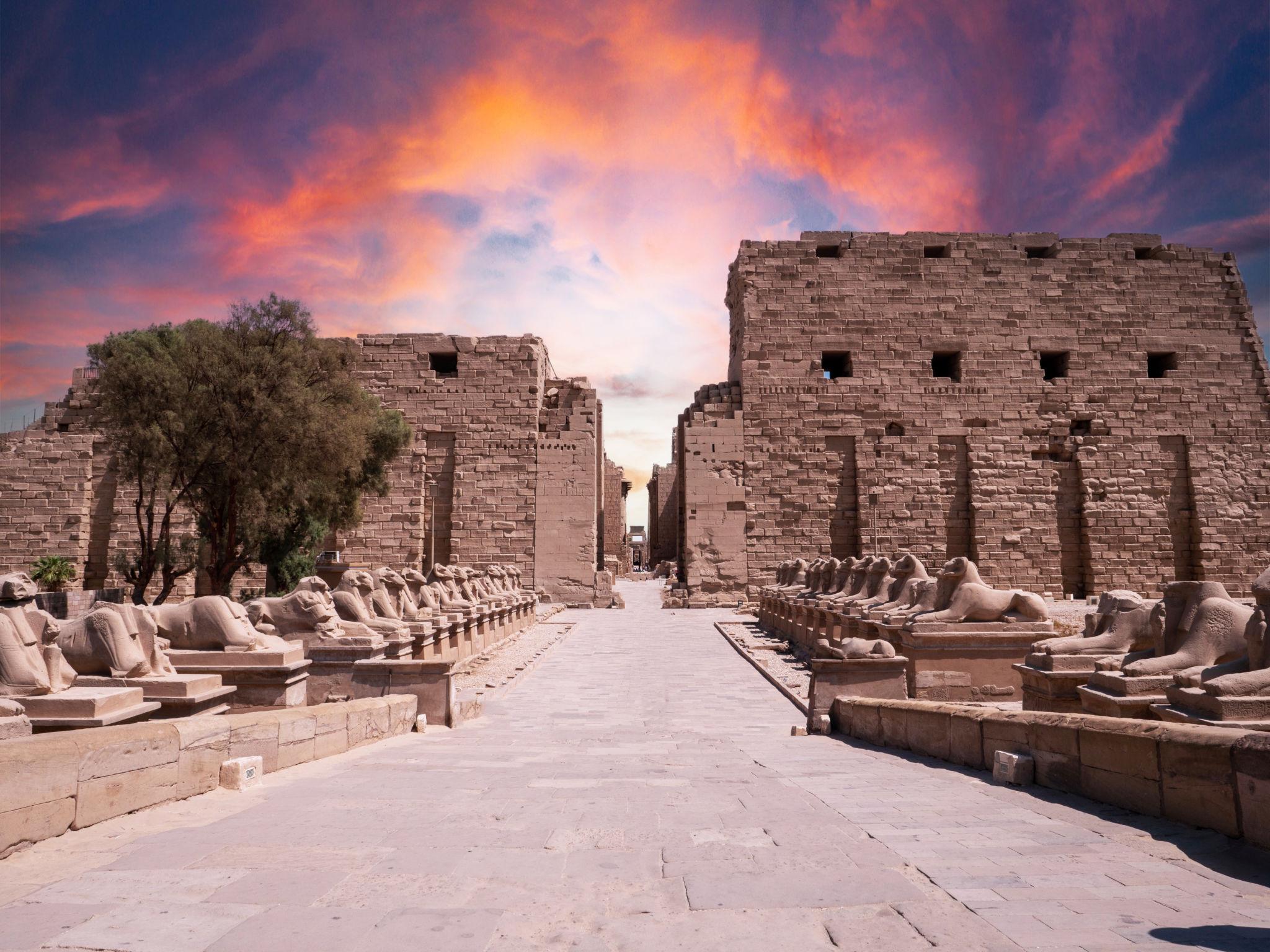 Avenue of sphinxes leading to Karnak's first pylon under a dramatic sunset