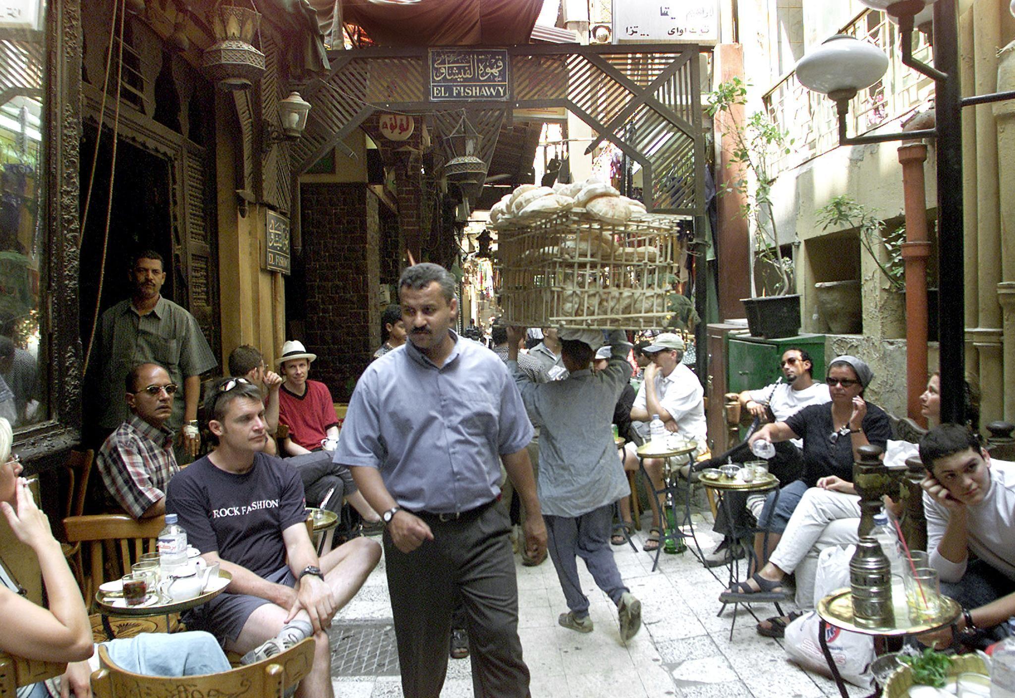 Busy alley at El Fishawy café in Khan el-Khalili with bread vendor and seated tourists