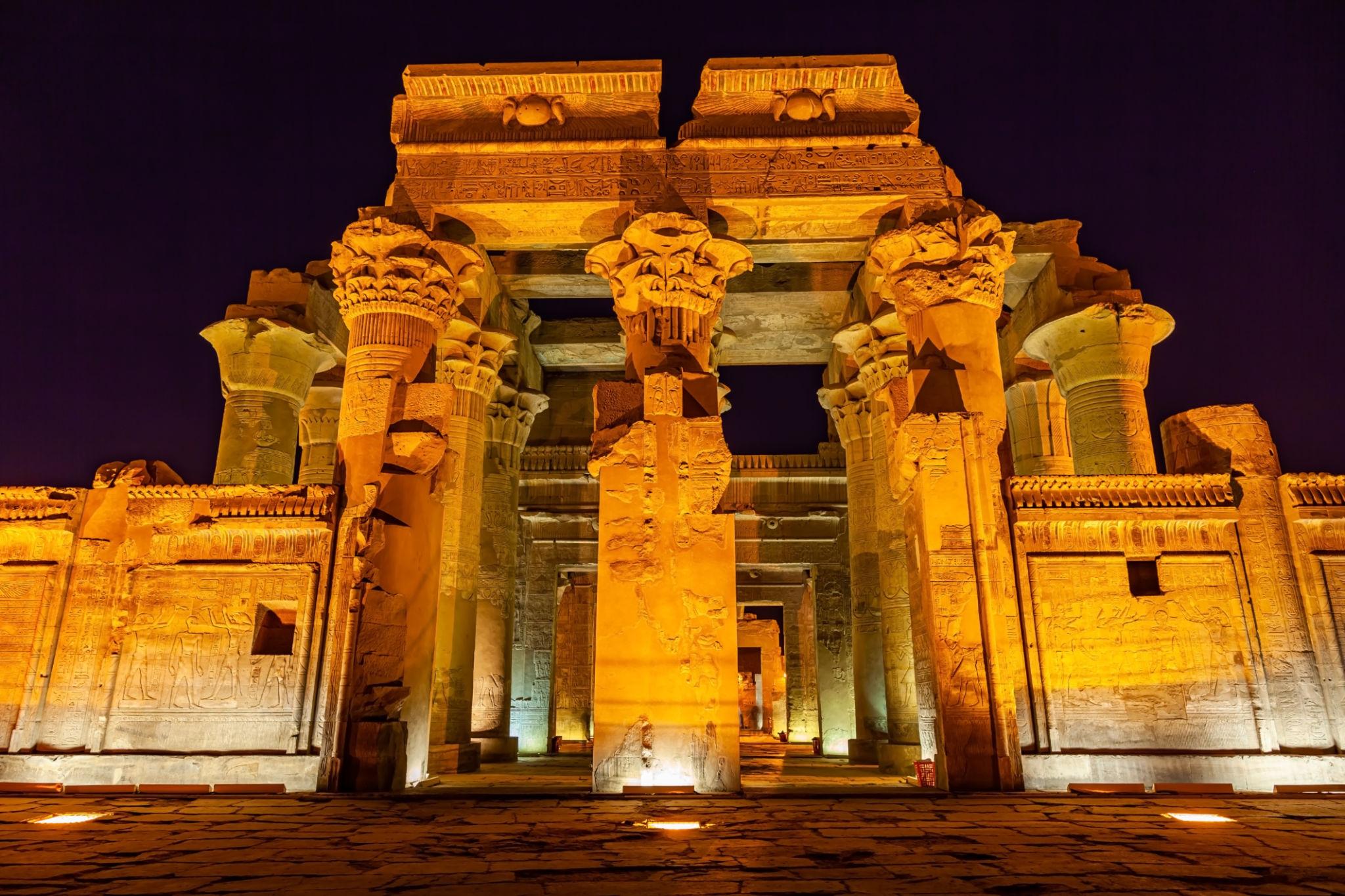 Kom Ombo Temple facade illuminated by warm lights against the night sky.