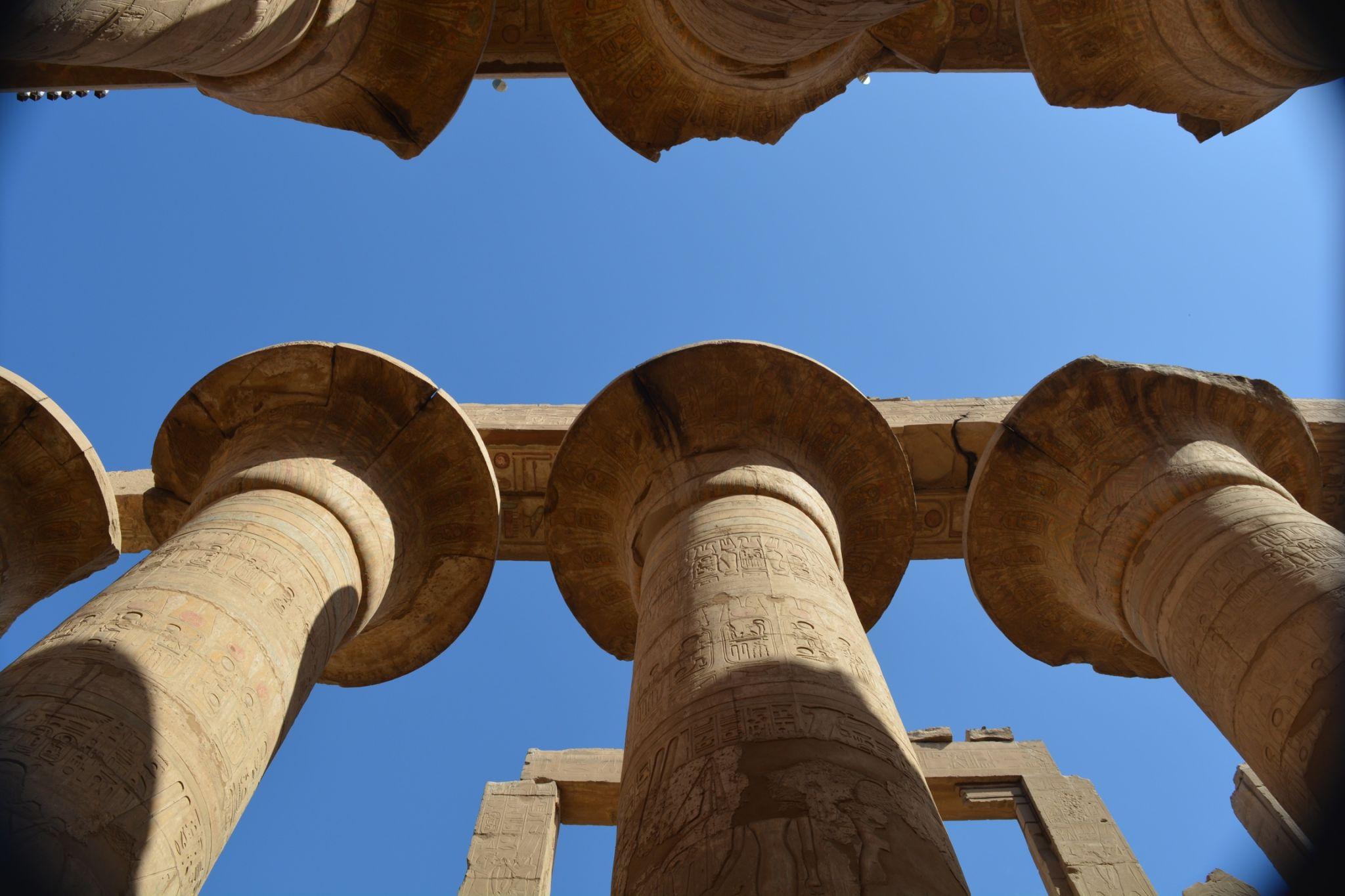 Papyrus column capitals viewed from below against vivid blue sky.
