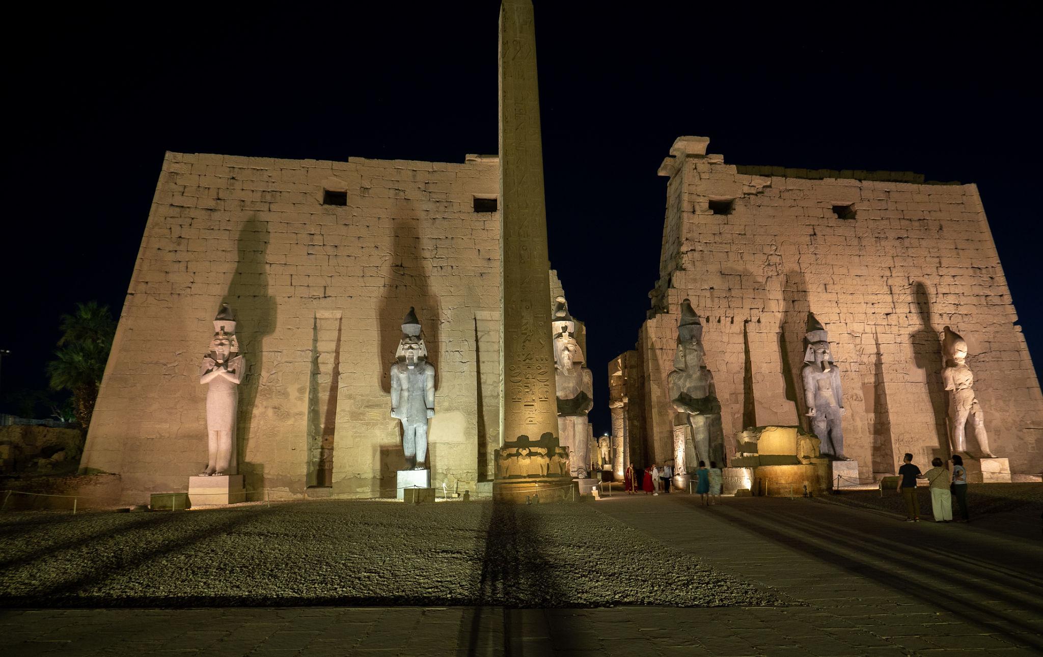 Frontal night view of Luxor Temple pylon with Ramses statues and obelisk.