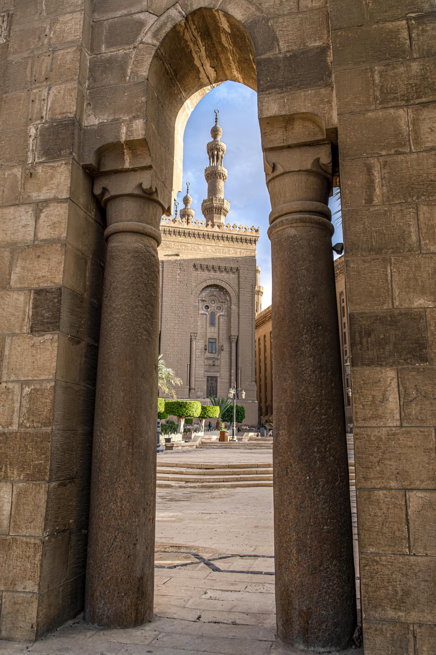 View through stone archway framing the soaring minaret of the Sultan Hassan complex