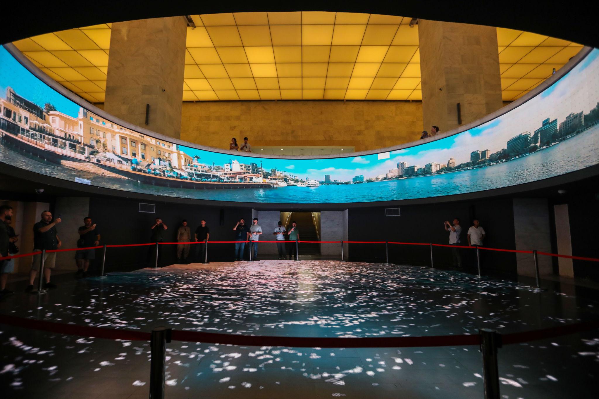 Visitors view a 360-degree curved screen displaying Cairo's Nile riverfront inside NMEC