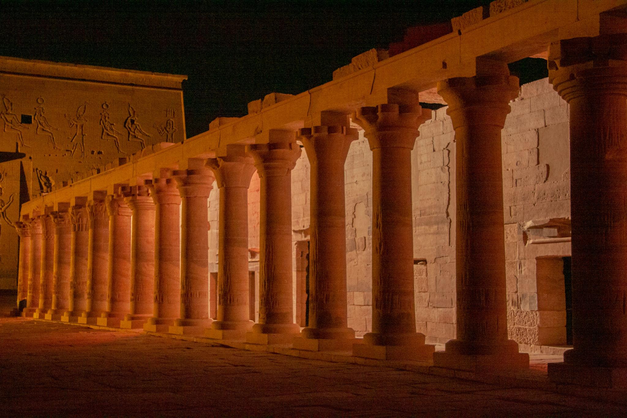 Illuminated ancient Egyptian columns and hieroglyph-carved walls of Philae Temple at night