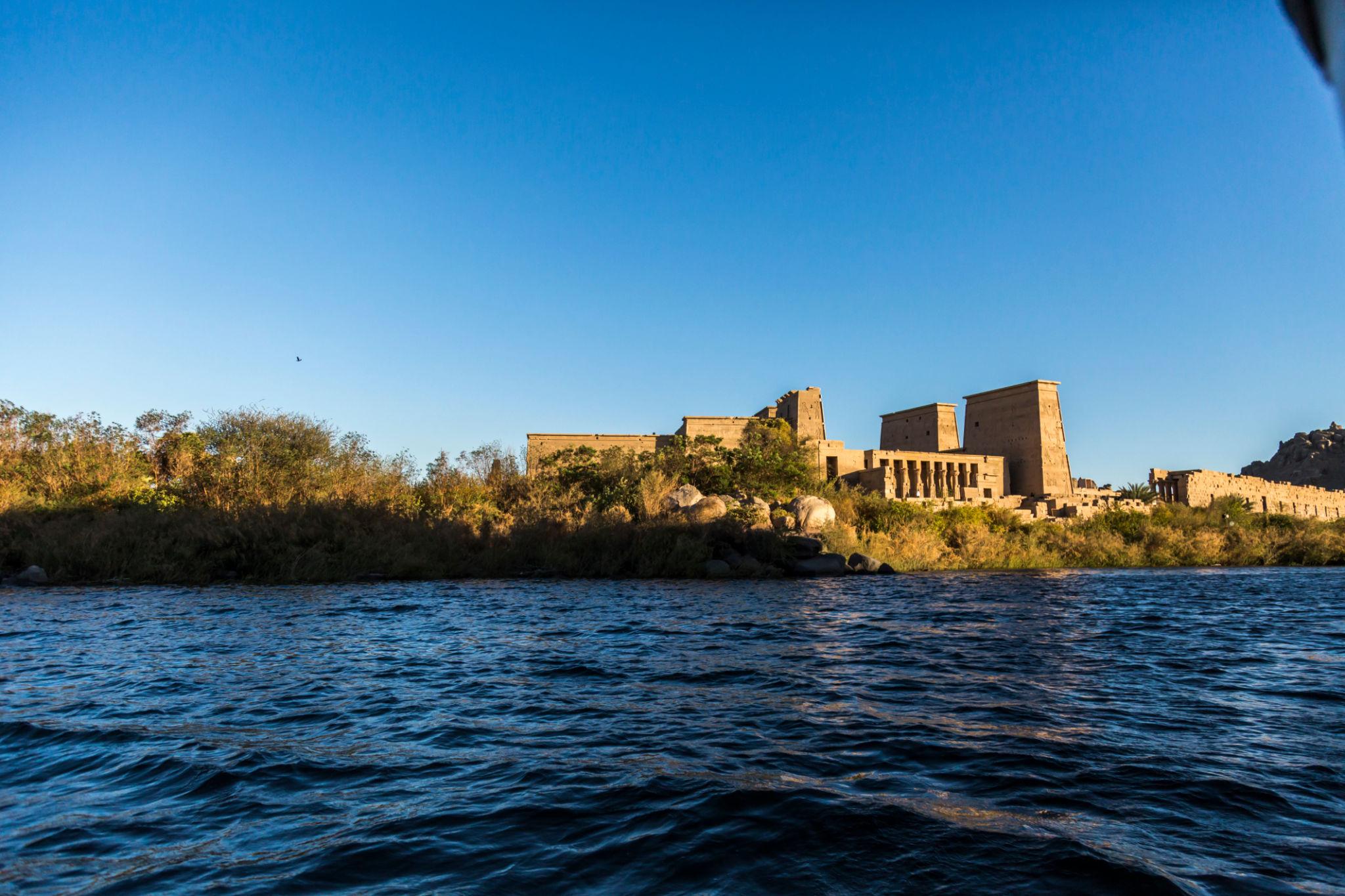 Philae Temple's twin pylons and colonnade seen from the Nile at golden hour