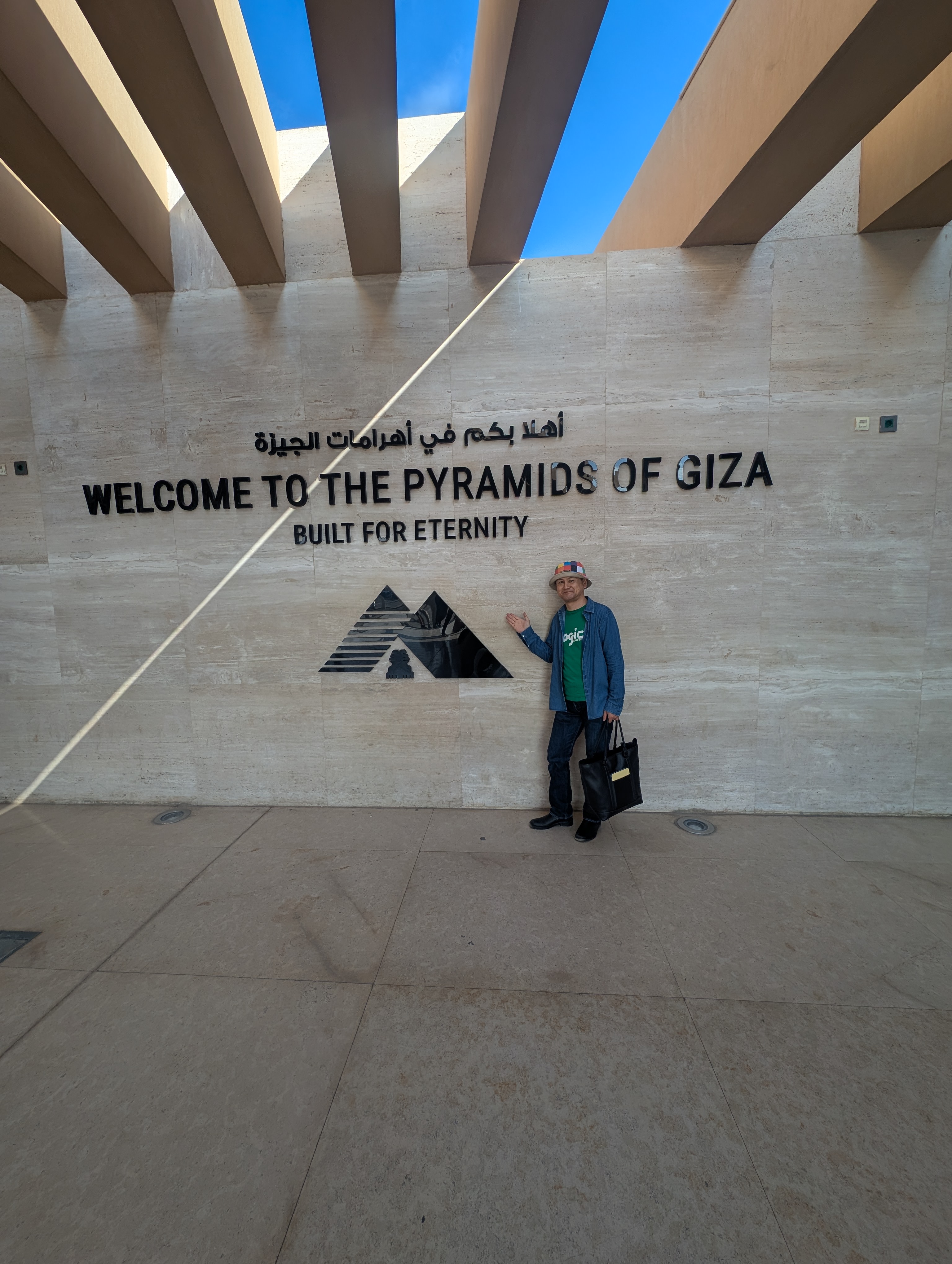 Visitor posing beside the Welcome to the Pyramids of Giza entrance sign