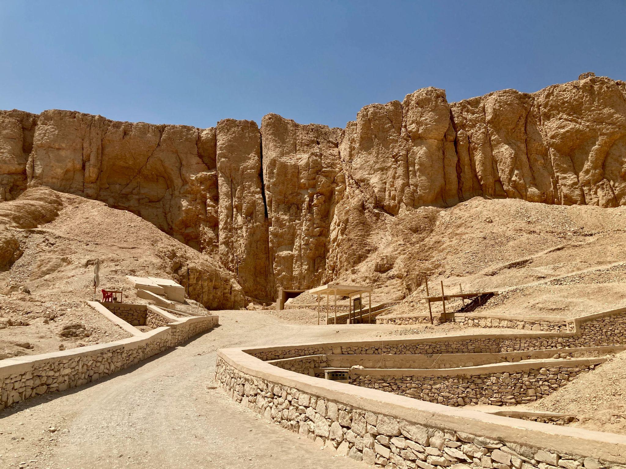 Panoramic view of pale limestone cliffs and tomb access ramps across the Valley of the Kings.
