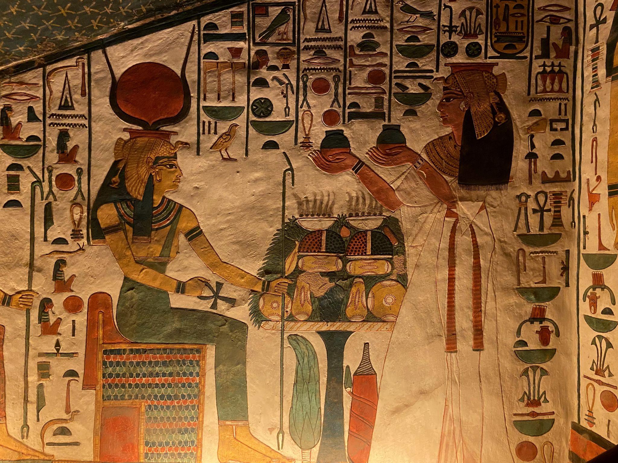 Nefertari offering to Hathor, seated with sun disk and cow horns, in her painted tomb.