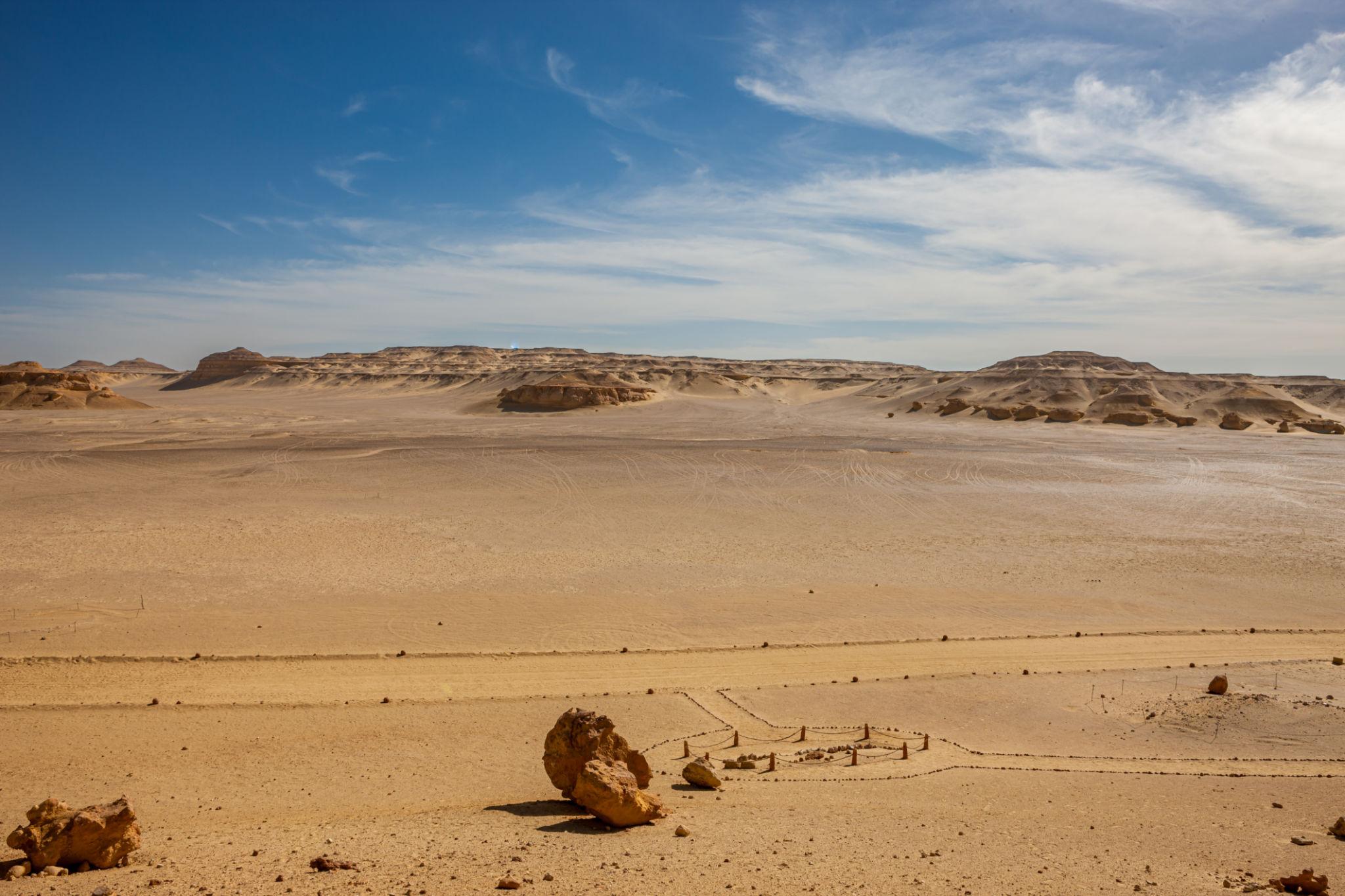 Panoramic view of the Fayoum desert plateau and fossil site at Wadi Al-Hitan under a blue sky